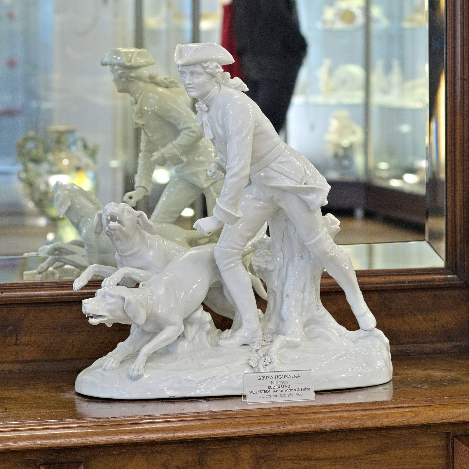 Biała porcelanowa grupa figuralna z myśliwym i psami w gablocie Muzeum Porcelany
