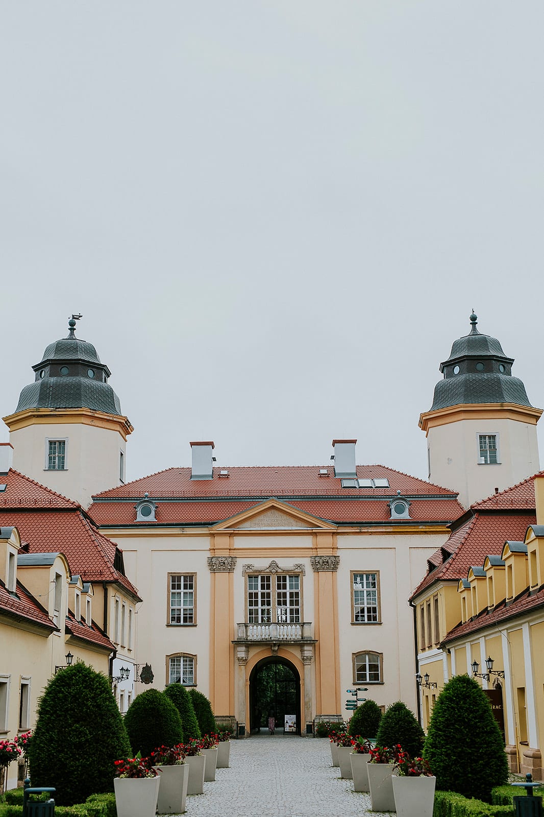 Symetryczny dziedziniec Budynku Bramnego Zamku Książ z wieżami i stożkowymi żywopłotami